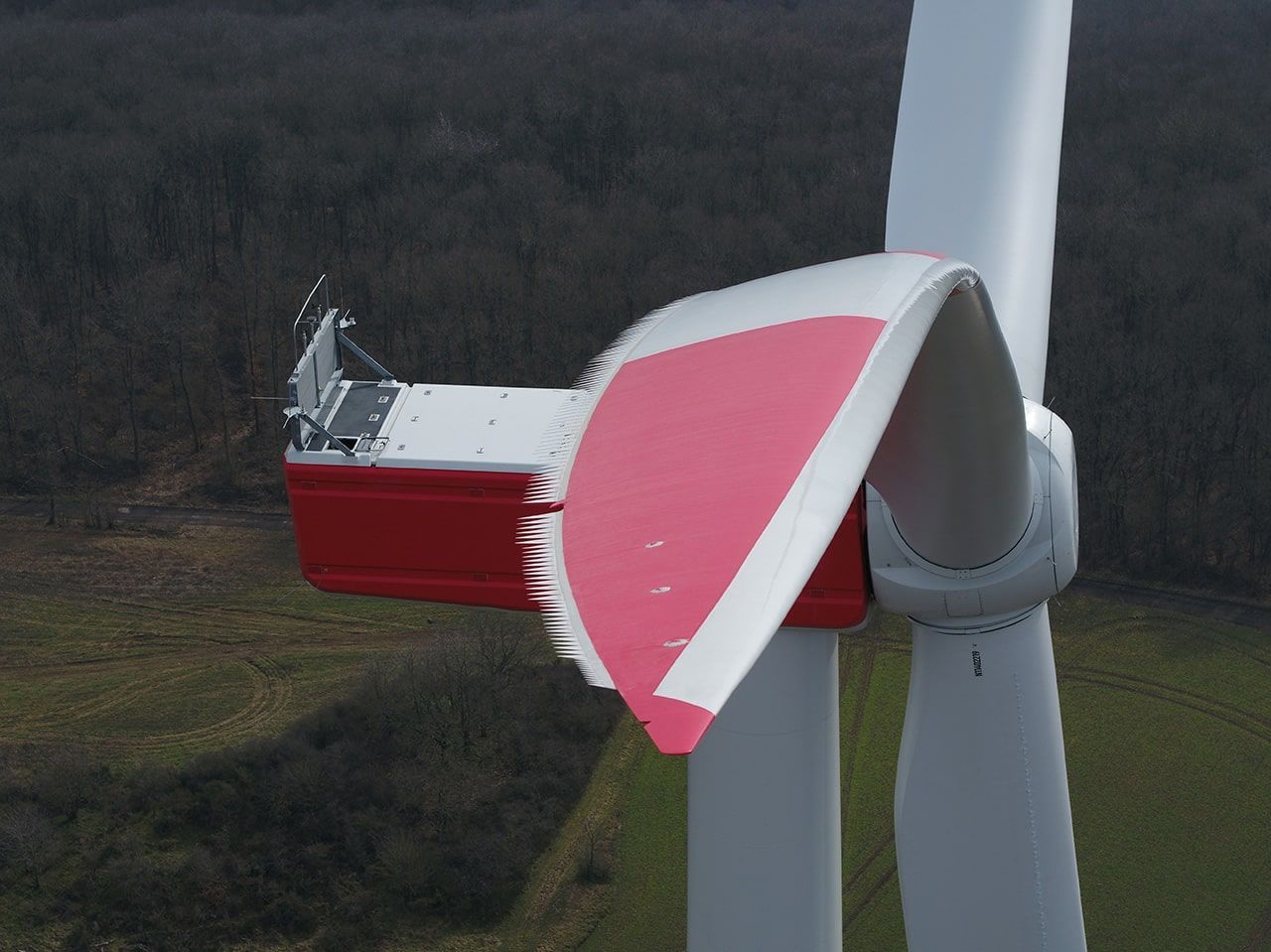 Nahaufnahme einer Windkraftanlage mit einem roten und weißen Kasten darauf, der die Technik der Turbine ergänzt.