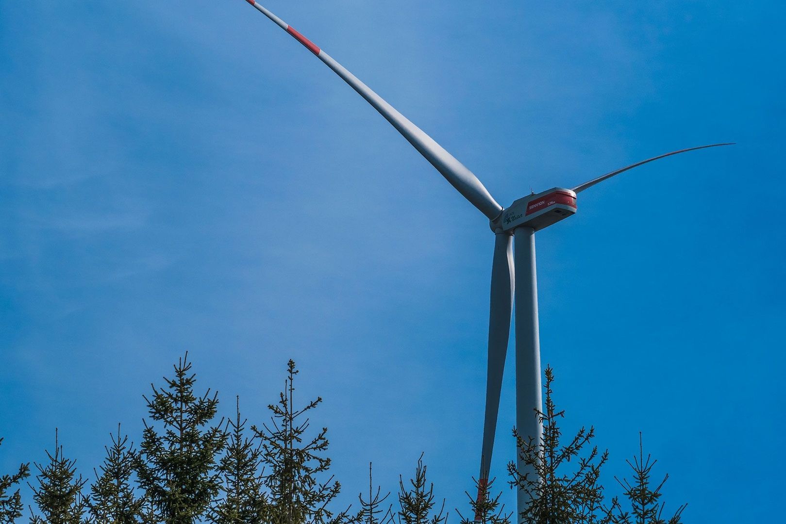 Eine Windkraftanlage vor einem strahlend blauen Himmel, der die saubere Energieerzeugung symbolisiert.